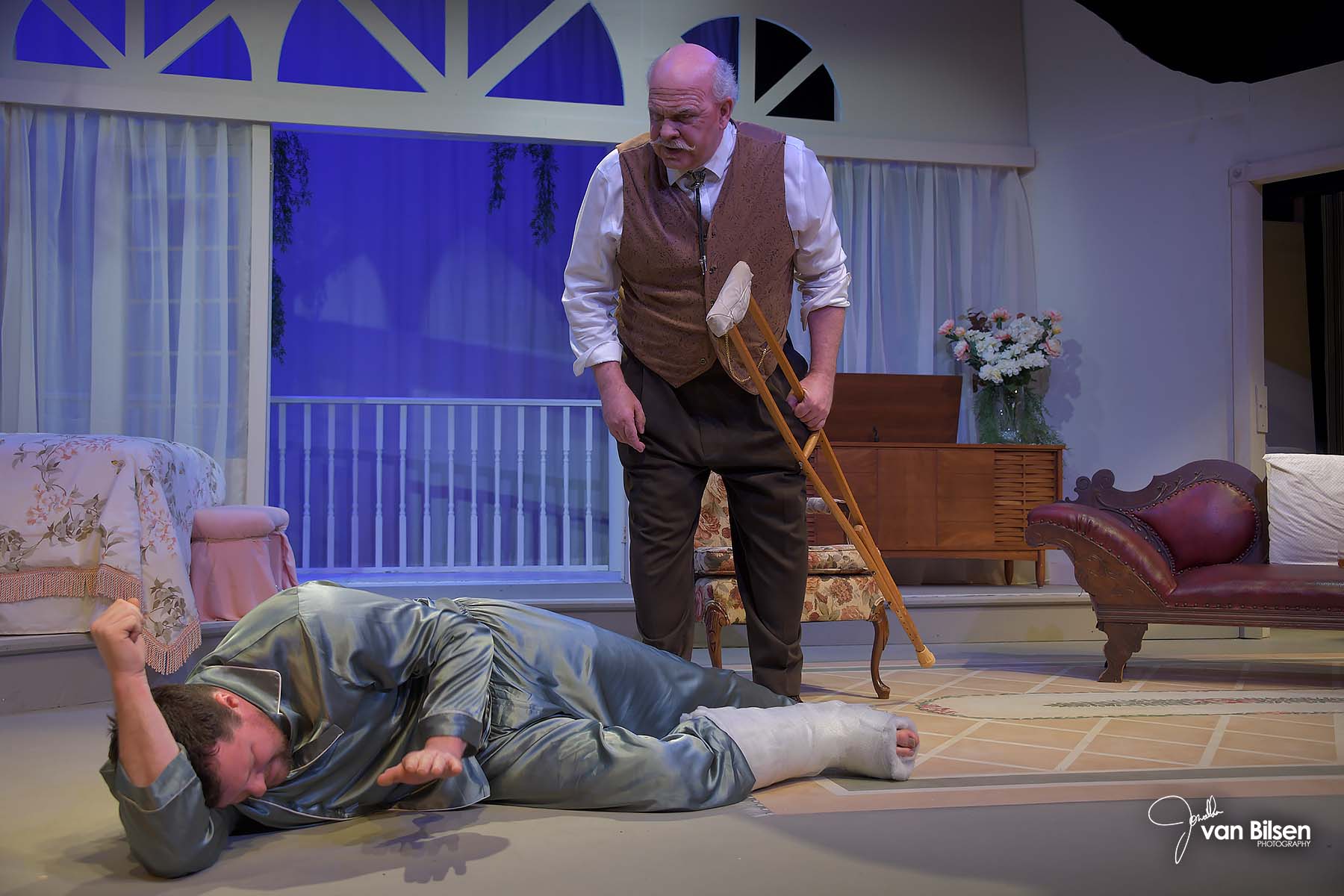 Gideon Heath as Big Daddy, holding a crutch and leaning over a fallen Brick, in Cat on a Hot Tin Roof